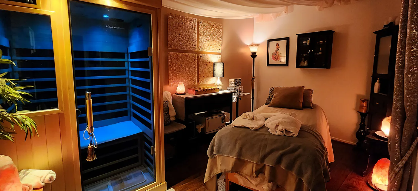 Infrared sauna beside a softly lit massage table in the treatment room