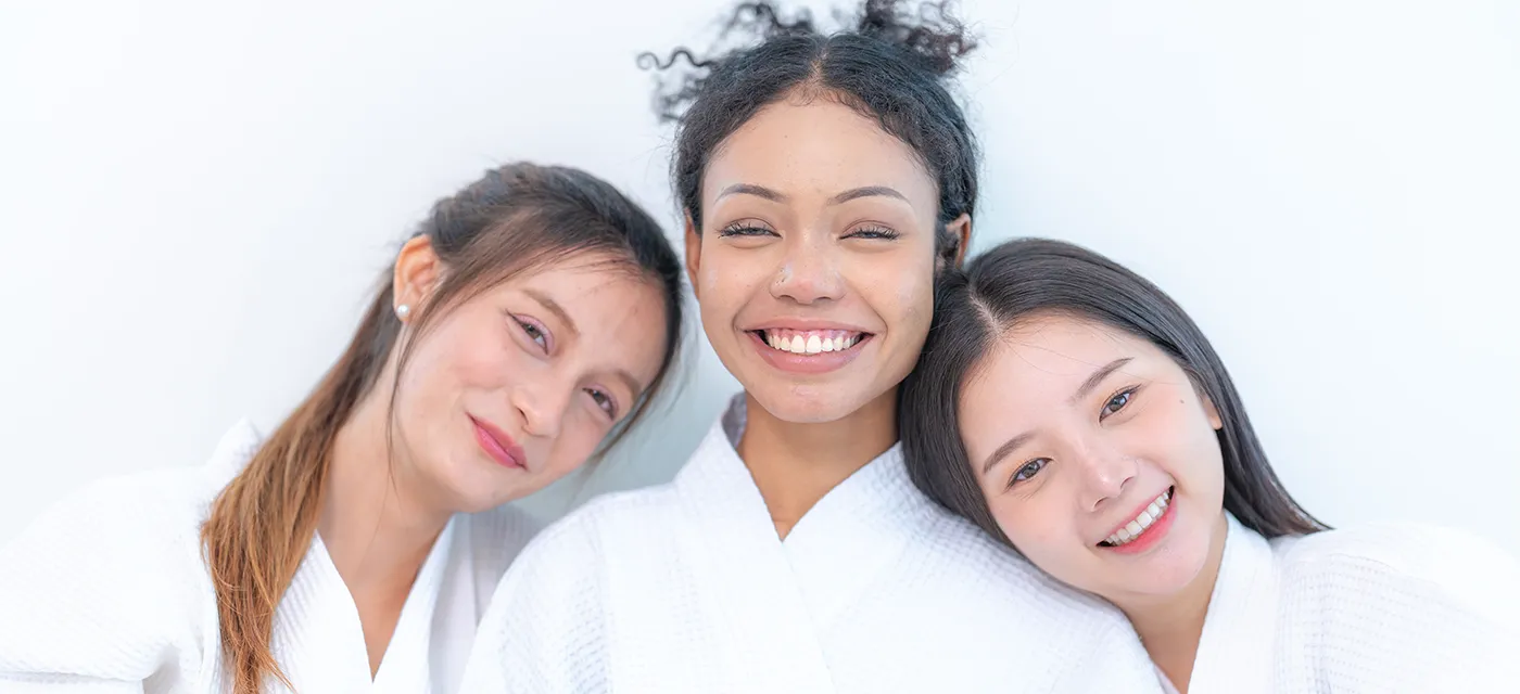 Three teen spa party guests in white robes, smiling