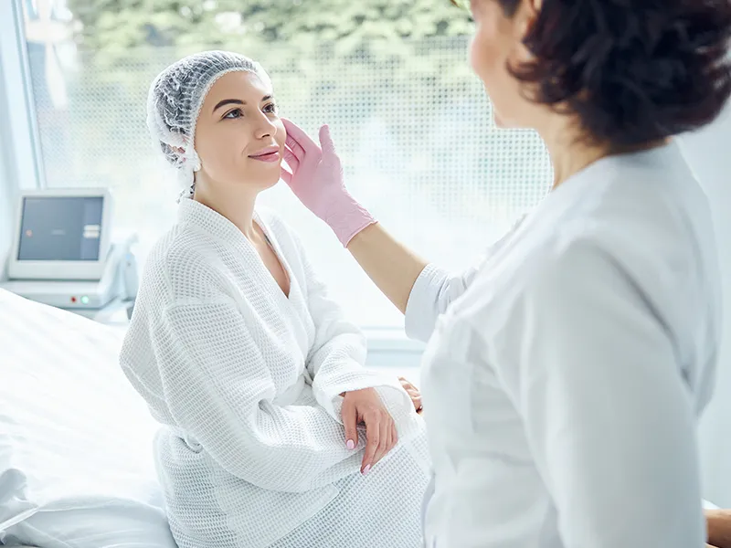 Esthetician gently assessing a guest's skin before an oncology skincare treatment